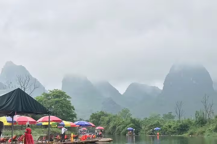 Tourists enjoying bamboo raft rides on the lush, misty rivers of Yangshuo, surrounded by stunning karst peaks.