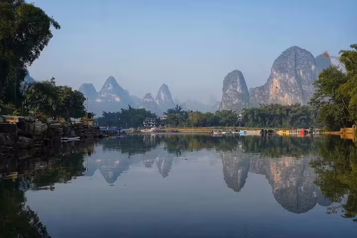 Scenic view of Yangshuo's karst mountains reflecting in a tranquil river, ideal for a biking and boat tour experience.