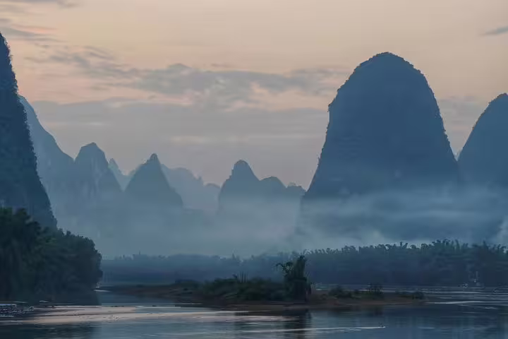 Misty karst mountains at sunrise in Yangshuo, perfect for a scenic biking and river tour adventure.