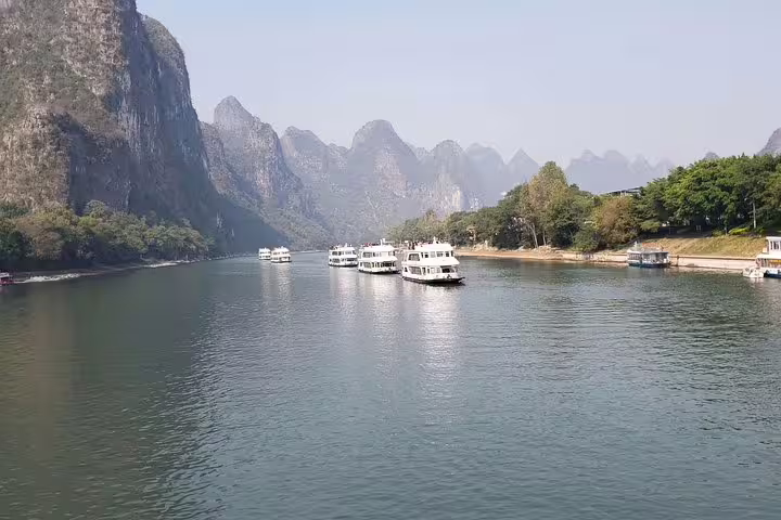 Tour boats cruising along the serene Li River with stunning karst peaks in Yangshuo, ideal for river tours.
