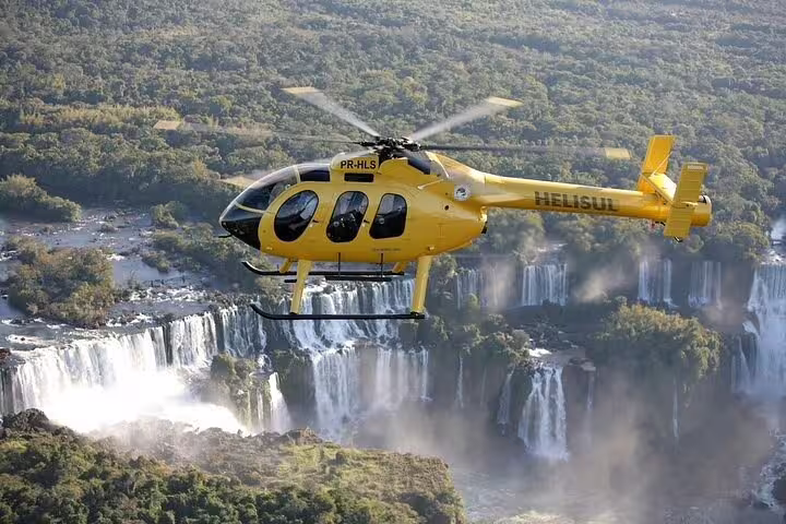 Yellow helicopter flying over Foz de Iguaçu waterfalls, offering a breathtaking aerial view of the stunning cascades.