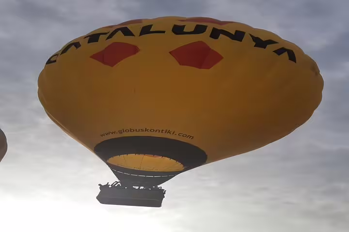 Yellow hot air balloon with 'Catalunya' branding soaring over Igualada during a scenic Montserrat tour.