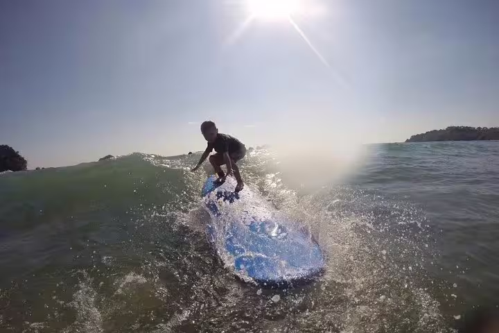 Young surfer mastering a wave under the bright sun during a Manuel Antonio surf lesson.