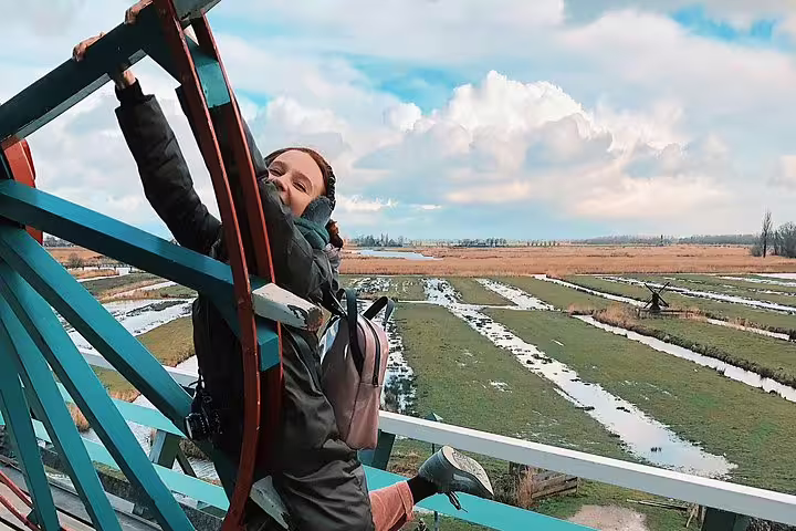 Traveler climbing a Zaanse Schans windmill with panoramic Dutch polder views on a private half-day tour