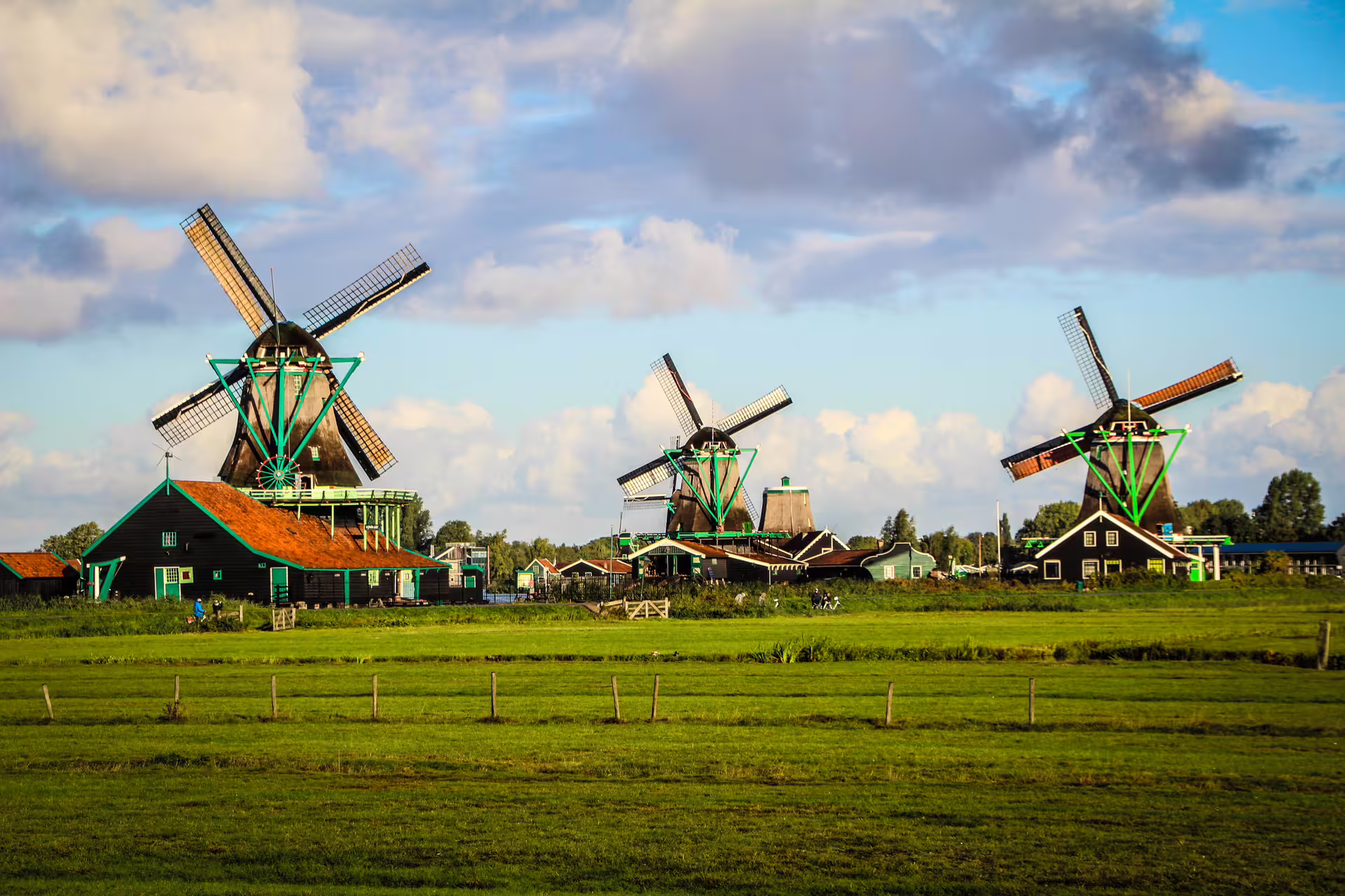 Scenic view of traditional windmills in Zaanse Schans against a blue sky, perfect for a cultural tour of the Netherlands.