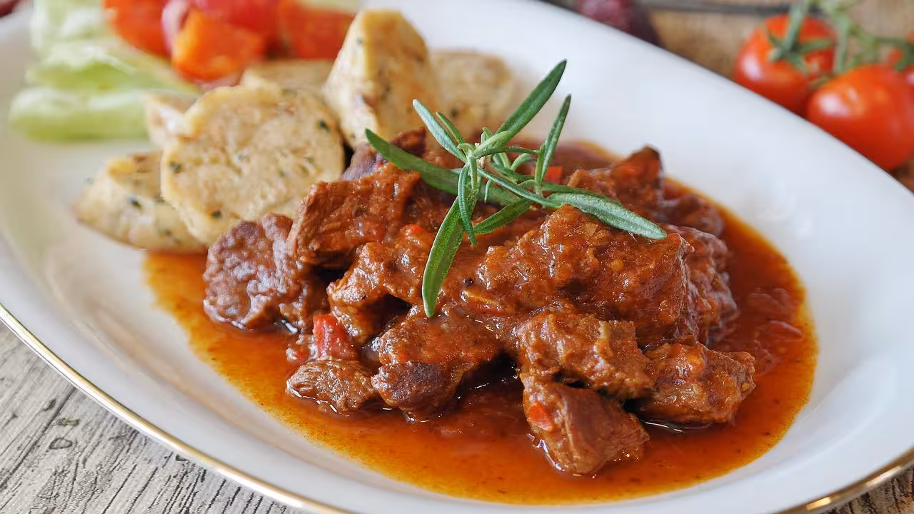 Plate of rich beef stew with vegetables and dumplings, a highlight of the Zahara Beef Festival culinary experience.