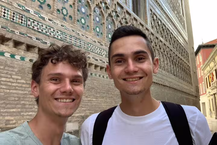 Smiling travelers at Zaragoza La Seo Cathedral exterior on a self-guided scavenger hunt and sights tour