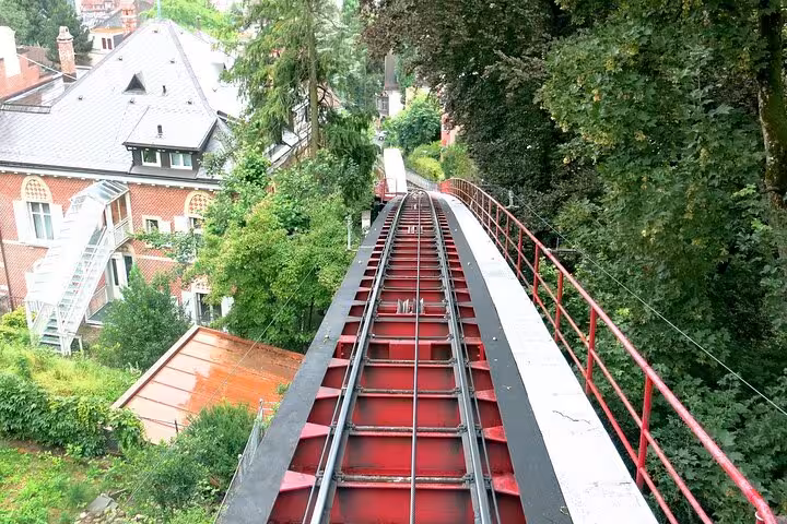Red tracks of a funicular railway cutting through lush greenery, ideal for Zurich's exciting transportation adventure.