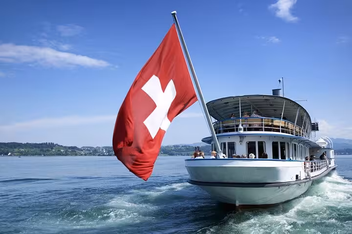 Scenic boat tour on Lake Zurich with Swiss flag waving in the breeze, part of Zurich transportation adventure.