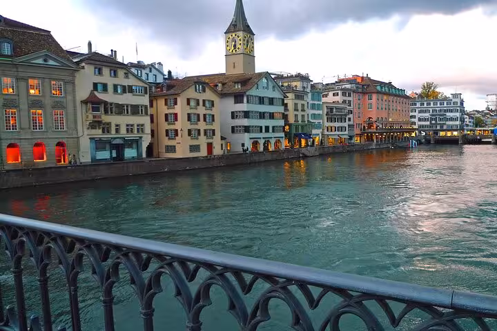 Scenic view of Zurich's Limmat River with historic buildings and clock tower, perfect for a transportation adventure.