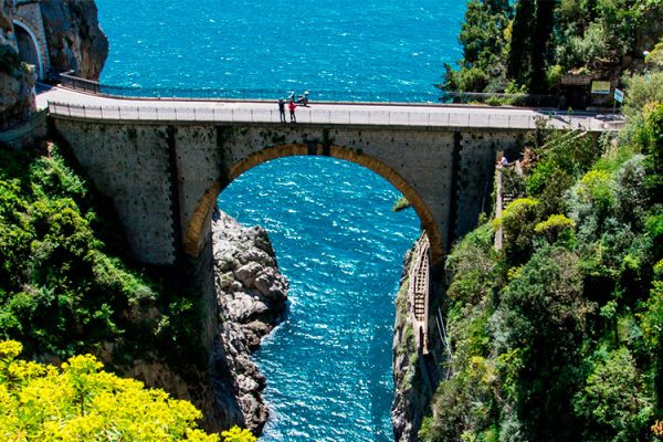 Fiordo di Furore, a hidden gem on Italy's Amalfi Coast, boasts a natural arch bridge, turquoise waters, and towering cliffs. Ideal for swimming, snorkeling, cliff-jumping, and hiking, it offers a tranquil escape with breathtaking views.