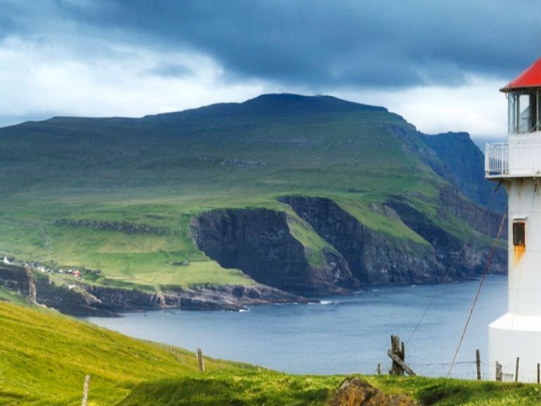 Established in 1927, Kallur Lighthouse graces Kalsoy's northern coast in the Faroe Islands. Perched on a dramatic cliff, this historic landmark offers breathtaking views of the rugged coastline, Atlantic Ocean, and neighboring islands.