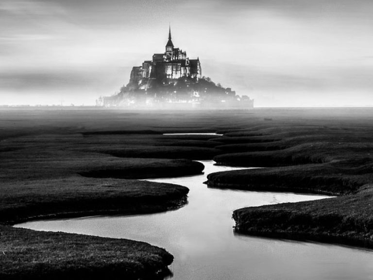 "Mont Saint-Michel, the 'Marvel of the West,' is a captivating island commune in Normandy, France. Nestled at the Couesnon River's mouth, it connects to the mainland via a causeway, drawing tourists worldwide as a UNESCO World Heritage site."
