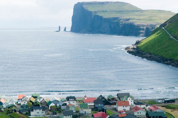 Tjørnuvík, a quaint village on Streymoy's northern coast in the Faroe Islands, captivates with its striking scenery, black sand beach, and traditional Faroese architecture, all nestled amidst majestic mountains.
