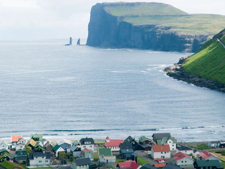 Tjørnuvík, a quaint village on Streymoy's northern coast in the Faroe Islands, captivates with its striking scenery, black sand beach, and traditional Faroese architecture, all nestled amidst majestic mountains.