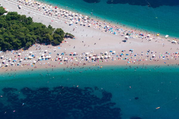 Zlatni rat beach in Croatia is famed for its distinctive horn-like shape, stretching into the Adriatic Sea. Its fine white pebbles are therapeutic for the skin, complementing the crystal-clear water ideal for swimming, snorkeling, and diving.