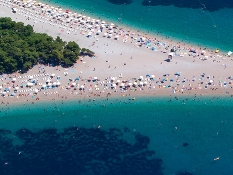 Zlatni rat beach in Croatia is famed for its distinctive horn-like shape, stretching into the Adriatic Sea. Its fine white pebbles are therapeutic for the skin, complementing the crystal-clear water ideal for swimming, snorkeling, and diving.