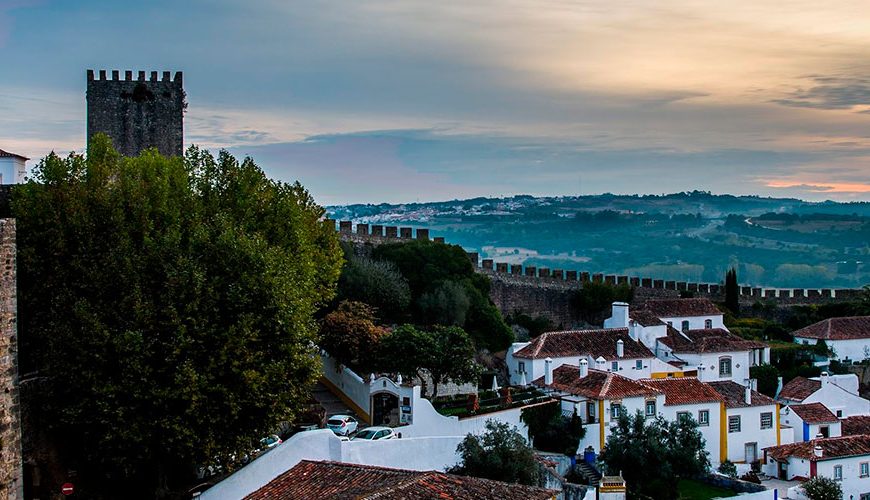 Visit Óbidos, the enchanted village - Óbidos is a charming medieval town located in the west of Portugal, known for its narrow cobbled streets, whitewashed houses adorned with flowers, and well-preserved castle walls.