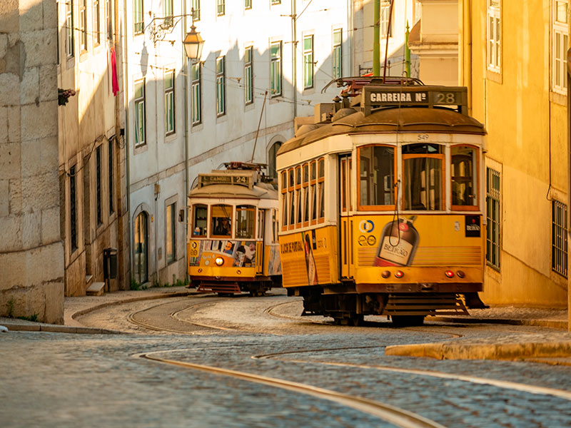 Lisbon Travel Guide: For a true taste of Lisbon’s past meshing with its present, hop on one of the iconic yellow trams. The most famous route, the 28 Tram, weaves through many of Lisbon’s most historic districts including Alfama, Graca, and Baixa. These trams don't just offer a convenient means of transport; they're an experience in themselves.